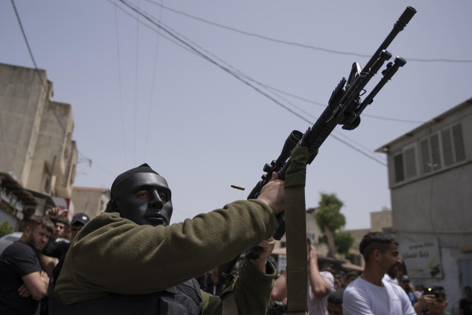 A masked Palestinian gunman shoots in the air during the funeral of Yahia Edwan, 27 at the West Bank village of Azzoun, near Qalqiliya, Saturday, April 30, 2022. Israeli troops shot and killed Edwan early Saturday, the Palestinian Health Ministry said. The Israeli army said it had opened fire after a group of suspects threw firebombs toward the soldiers. (AP Photo/Nasser Nasser)