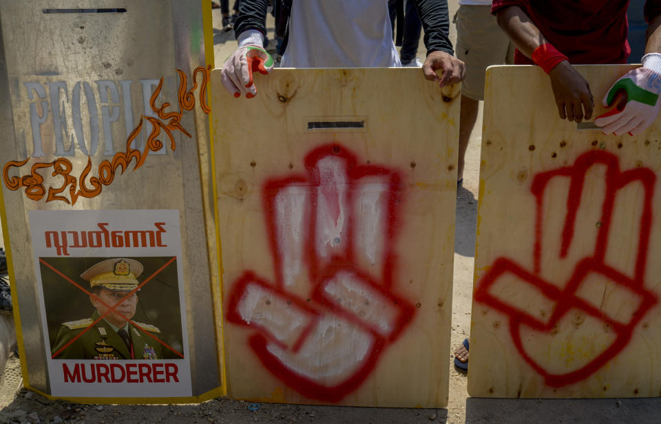 Anti-coup protesters stand behind a line of makeshift shields marked with three-fingered salute and defaced image of Commander in chief, Senior Gen. Min Aung Hlaing as they gather to protest in Yangon, Myanmar Tuesday, March 9, 2021. Demonstrators in Myanmar's biggest city came out Monday night for their first mass protests in defiance of an 8 p.m. curfew, seeking to show support for an estimated 200 students trapped by security forces in a small area of one neighborhood. (AP Photo)