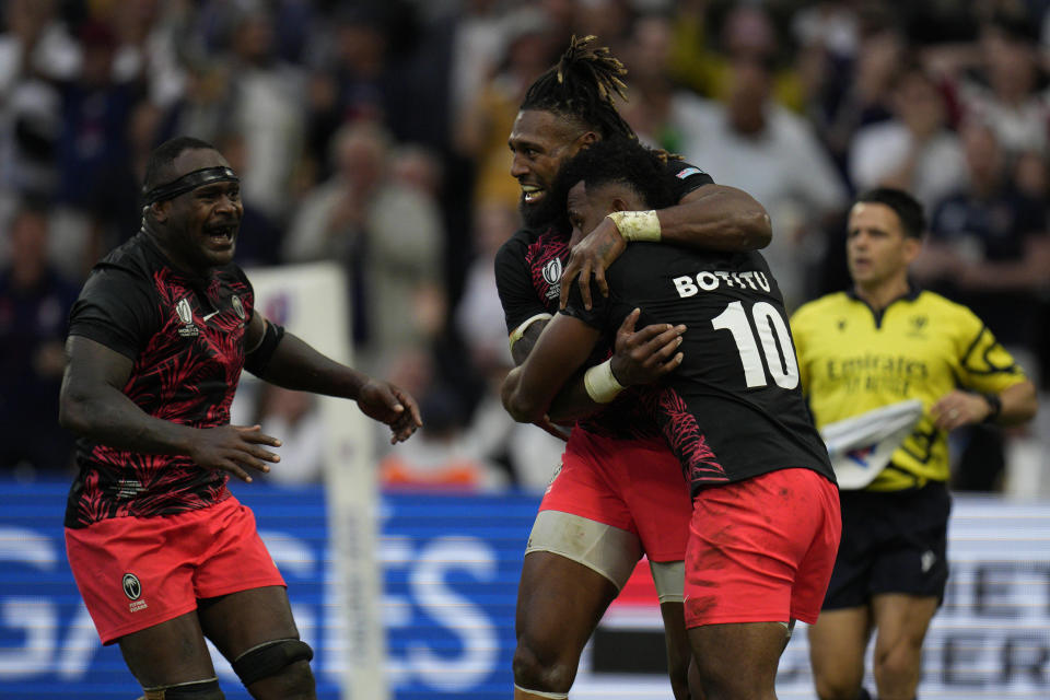 Teammates congratulate Fiji's Vilimoni Botitu, right, after he scored a try despite England's Danny Care during the Rugby World Cup quarterfinal match between England and Fiji at the Stade de Marseille in Marseille, France, Sunday, Oct. 15, 2023. (AP Photo/Daniel Cole)