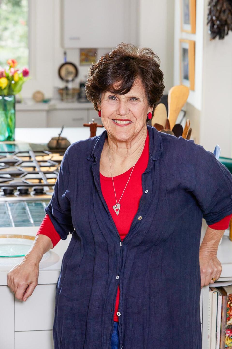 A smiling woman stands in a kitchen