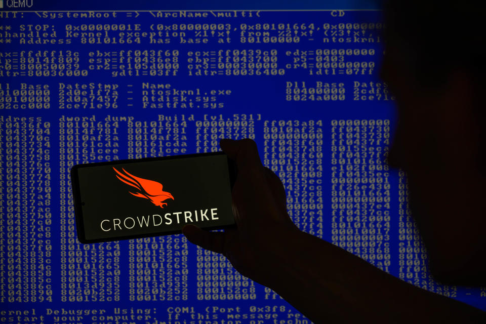 El logotipo de CrowdStrike se muestra en un teléfono inteligente con una pantalla azul de Windows visible en el fondo en esta ilustración fotográfica en Bruselas, Bélgica, el 19 de julio de 2024. (Foto de Jonathan Raa/NurPhoto vía Getty Images)