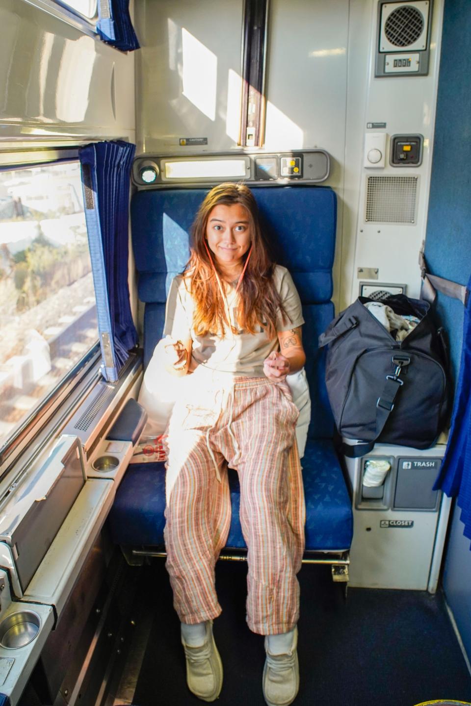 The author sits in a Roomette with a window on the left side