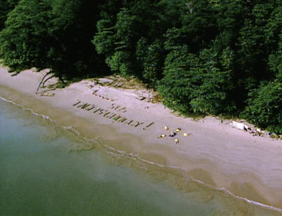 A beach with a sign reading "SOS Tagi is Groggy" on Survivor: Borneo