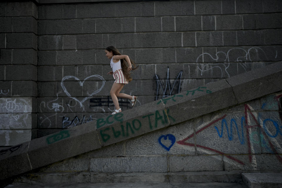 A girl plays in Kyiv, Ukraine, Friday, June 10, 2022. With war raging on fronts to the east and south, the summer of 2022 is proving bitter for the Ukrainian capital, Kyiv. The sun shines but sadness and grim determination reign. (AP Photo/Natacha Pisarenko)