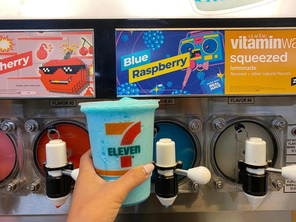 A hand filling up a large 7/11 cup with blue raspberry slurpee