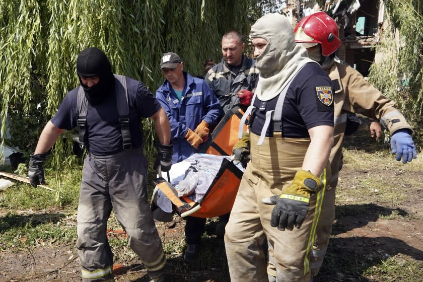 Rescuers move a covered body of a woman killed by Russian missile attack on Monday in Chuhuiv, Kharkiv region, Ukraine, Tuesday, July 26, 2022. (AP Photo/Andrii Marienko)