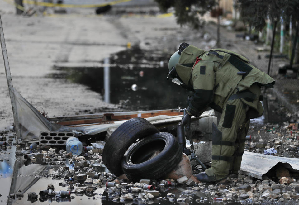 A Lebanese police bomb disposal expert prepares to destroy an unexploded hand grenade that was throw by protesters on Thursday night inside the parking of an official government office, during a protest against deteriorating living conditions and strict coronavirus lockdown measures, in Tripoli, Lebanon, Friday, Jan. 29, 2021. (AP Photo/Hussein Malla)