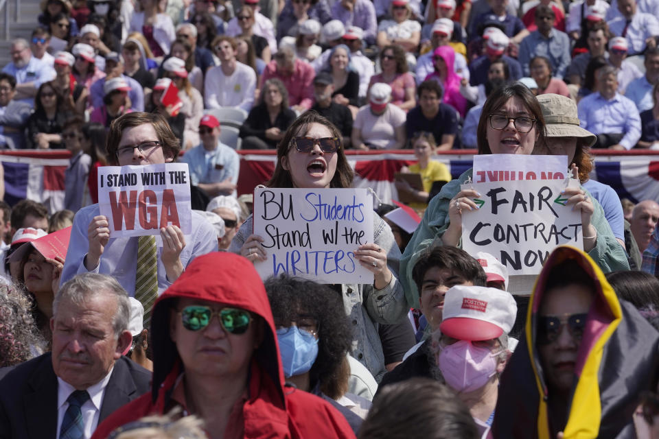 People in the audience display signs in support of the Hollywood writers' strike during an address by David Zaslav, president and CEO of Warner Bros. Discovery, at Boston University commencement ceremonies, Sunday, May 21, 2023, in Boston. (AP Photo/Steven Senne)