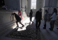 People kiss the cross on the altar in the Holy Savior Cathedral, damaged by shelling by Azerbaijan's artillery, during a military conflict in Shushi, the separatist region of Nagorno-Karabakh, Saturday, Oct. 24, 2020. The heavy shelling forced residents of Stepanakert, the regional capital of Nagorno-Karabakh, into shelters, as emergency teams rushed to extinguish fires. Nagorno-Karabakh authorities said other towns in the region were also targeted by Azerbaijani artillery fire. (AP Photo)