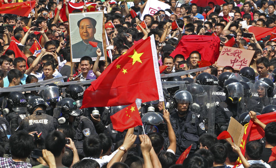 Chinese demonstrators raise national flags as they confront riot policemen during a protest against Japan in Shenzhen, China Sunday, Sept. 16, 2012. Protesters in China began another day of demonstrations against Japan, after protests over disputed islands spread across numerous cities and at times turned violent. (AP Photo/Apple Daily) HONG KONG OUT, TAIWAN OUT, NO SALES