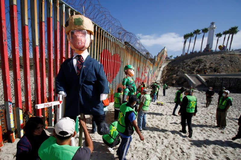 Migrants and members of civil society hold pinatas during a protest in Tijuana