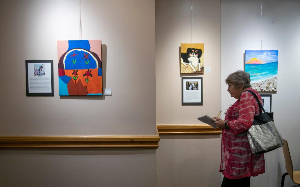 Dee Stevenson, a member of the Friends of the Cape Coral Library, looks at the artwork in the gallery at the library.