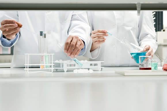 Two scientists side by side in lab, running tests with lab equipment.