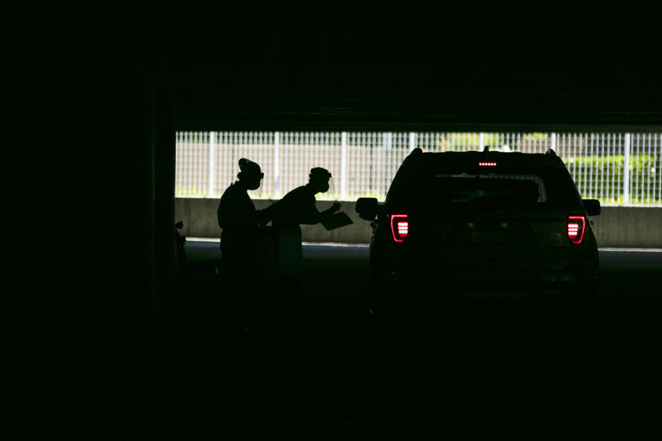 FILE - In this July 16, 2020, file photo, two physician assistants work at a COVID-19 drive-thru testing site set up at the Anaheim Convention Center in Anaheim, Calif. The torrid coronavirus summer across the Sun Belt is easing after two disastrous months that brought more than 35,000 deaths. (AP Photo/Jae C. Hong, File)