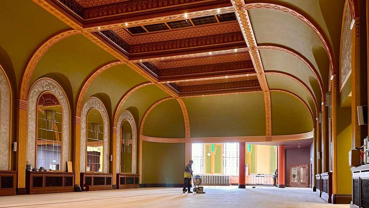 A worker polishes a large wooden floor inside Bradford Live