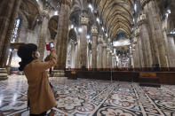 FILE - In this Monday, March 2, 2020 file photo, a tourist wearing a face mask takes pictures inside the Duomo gothic cathedral as it reopened to the public after being closed due to the COVID-19 virus outbreak in northern Italy, in Milan. The focal point of the coronavirus emergency in Europe, Italy, is also the region's weakest economy and is taking an almighty hit as foreigners stop visiting its cultural treasures or buying its prized artisanal products, from fashion to food to design. Europe’s third-largest economy has long been among the slowest growing in the region and is the one that is tallying the largest number of virus infections outside Asia. (Claudio Furlan/LaPresse via AP, File)