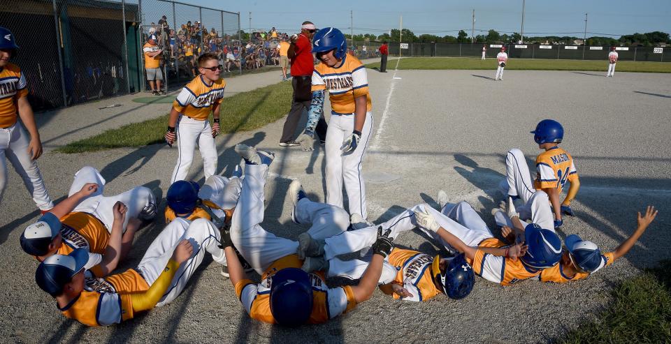 The Ida players fall down as part of a celebration of Bradley Healy's two-run homer during an 11-1 win over Bedford Elite Tuesday in the 63rd Monroe County Fair Baseball Tournament.