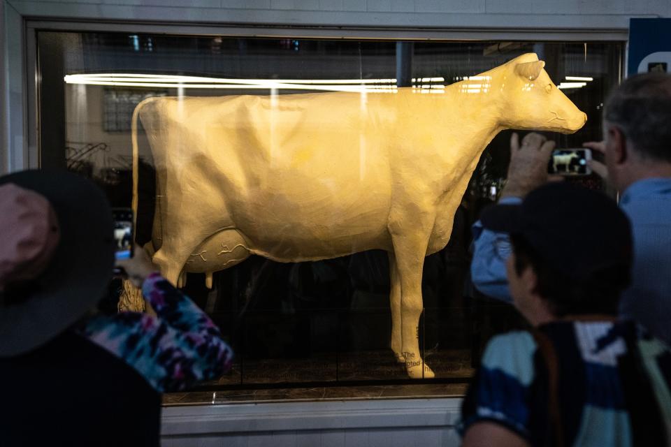 Fairgoers stop to view the butter cow on the first day of the Iowa State Fair, on Thursday, Aug. 10, 2023, in Des Moines.