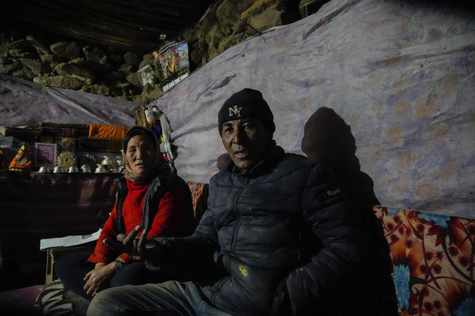 Nomad Tsering Angchuk, right, talks to The Associated Press as he sits with his wife, Dolma Angmo, left, inside their mud and stone house in remote Kharnak village in the cold desert region of Ladakh, India, Sunday, Sept. 17, 2022. Angchuk is determined to herd his flock of fine cashmere-producing goats in the treeless Kharnak village, a hauntingly beautiful but unforgiving, cold mountainous desert. (AP Photo/Mukhtar Khan)