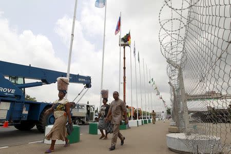 People walk past flags of countries whose representatives are expected to attend the inauguration of President-elect Muhammadu Buhari on Friday, at the Eagle Square in Abuja, Nigeria May 27, 2015. REUTERS/Afolabi Sotunde