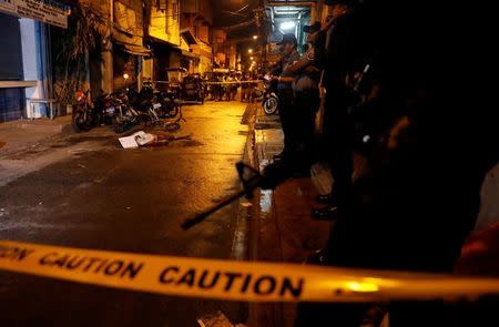 Policemen stand guard near the body of a man killed during what police said was a drug related vigilante killing in Pasig, Metro Manila, Philippines February 1, 2017. REUTERS/Erik De Castro