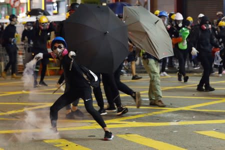 An anti-extradition bill demonstrator throws back a tear gas canister at the police during protests in Causeway Bay, Hong Kong