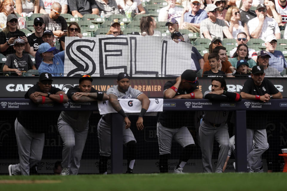 Fans hold up signs as the Chicago White Sox players watch during the ninth inning of a baseball game against the Milwaukee Brewers, Sunday, June 2, 2024, in Milwaukee. (AP Photo/Aaron Gash)