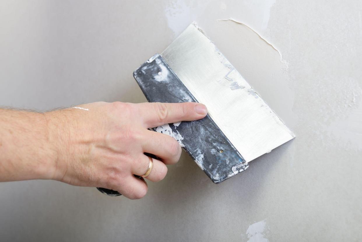 repairman plastering dry-stone wall