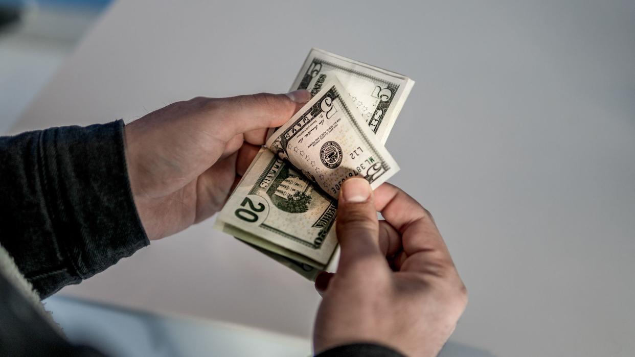 Unrecognizable young man counting US Dollar bills.