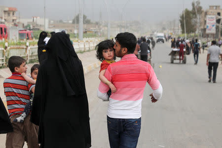 A displaced Iraqi man kisses his daughter as the battle between the Iraqi Counter Terrorism Service and Islamic State militants continues nearby, in western Mosul, Iraq, April 23, 2017. REUTERS/Marko Djurica