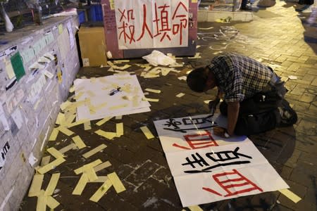 Lou Tit-Man, 73, writes a protest sign outside Mong Kok police station in Hong Kong