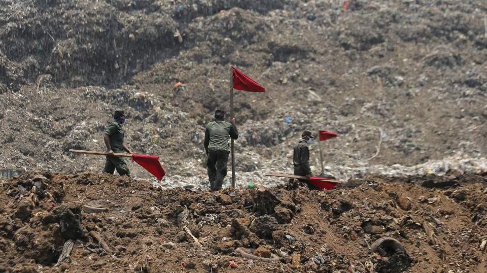 Sri Lankan army soldiers erect red flags to demarcate danger zones following the collapse of a garbage mound in Meetotamulla, on the outskirts of Colombo, Sri Lanka, Colombo, Sri Lanka, Monday, April 17, 2017. Rescuers on Monday were digging through heaps of mud and trash that collapsed onto a clutch of homes near a garbage dump outside Sri Lanka's capital, killing dozens and possibly burying dozens more. (AP Photo/Eranga Jayawardena)