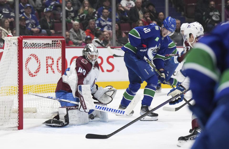 Colorado Avalanche goalie Alexandar Georgiev, left, makes a save as Vancouver Canucks' Elias Pettersson watches during the first period of an NHL hockey game Thursday, Jan. 5, 2023, in Vancouver, British Columbia. (Darryl Dyck/The Canadian Press via AP)