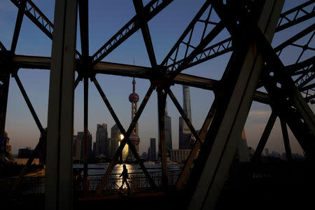 FILE PHOTO: A man walks on a bridge in front of the financial district of Pudong in Shanghai, China, December 8, 2017. REUTERS/Aly Song/File Photo