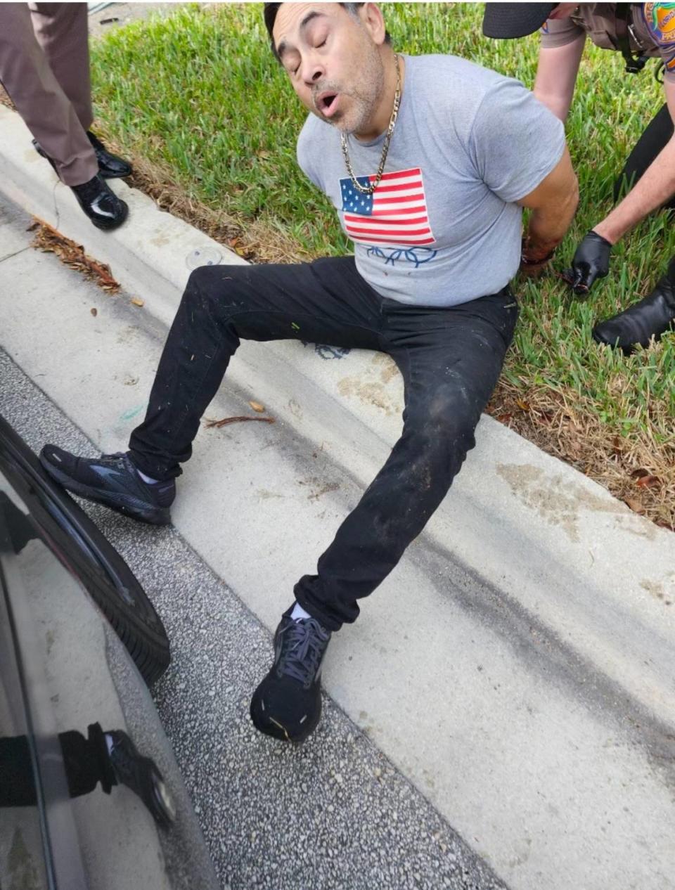 Police handcuff Ricardo Jimenez on a curb in Weston Tuesday, Jan. 2, 2024, after police say he crashed his Porsche into a Florida Highway Patrol trooper’s car on I-75 in Weston.