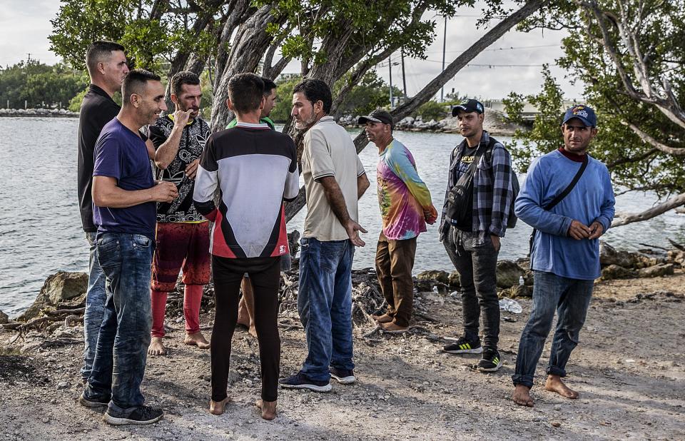 Members of two groups of Cuban migrants from Matanzas, Cuba, stand in the sun on the side of U.S. 1 in the Middle Keys island Duck Key, Fla., on Monday, Jan. 2, 2023. They said they have been standing there waiting to be picked up by U.S. Border Patrol agents since arriving in two rustic vessels. (Pedro Portal/Miami Herald via AP)