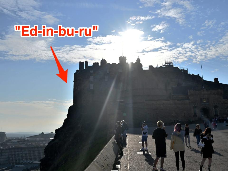 The sun sets behind Edinburgh Castle as people wander in front of it
