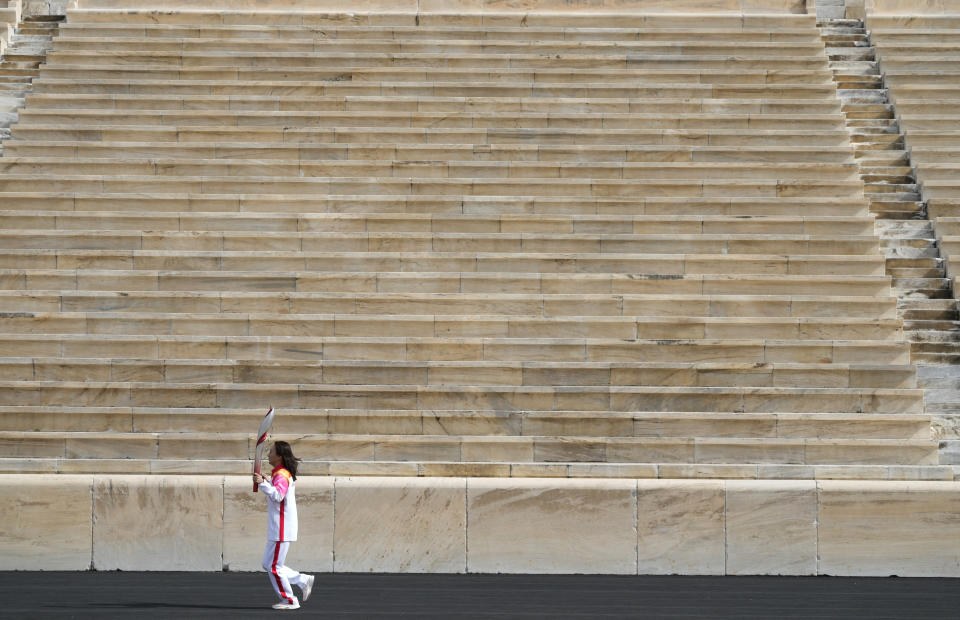 China's Olympic ski athlete Li Nina runs with the torch during the Olympic flame handover ceremony at Panathinean stadium in Athens, Greece, Tuesday, Oct. 19, 2021. The flame will be transported by torch relay to Beijing, China, which will host the Feb. 4-20, 2022 Winter Olympics. (AP Photo/Thanassis Stavrakis)