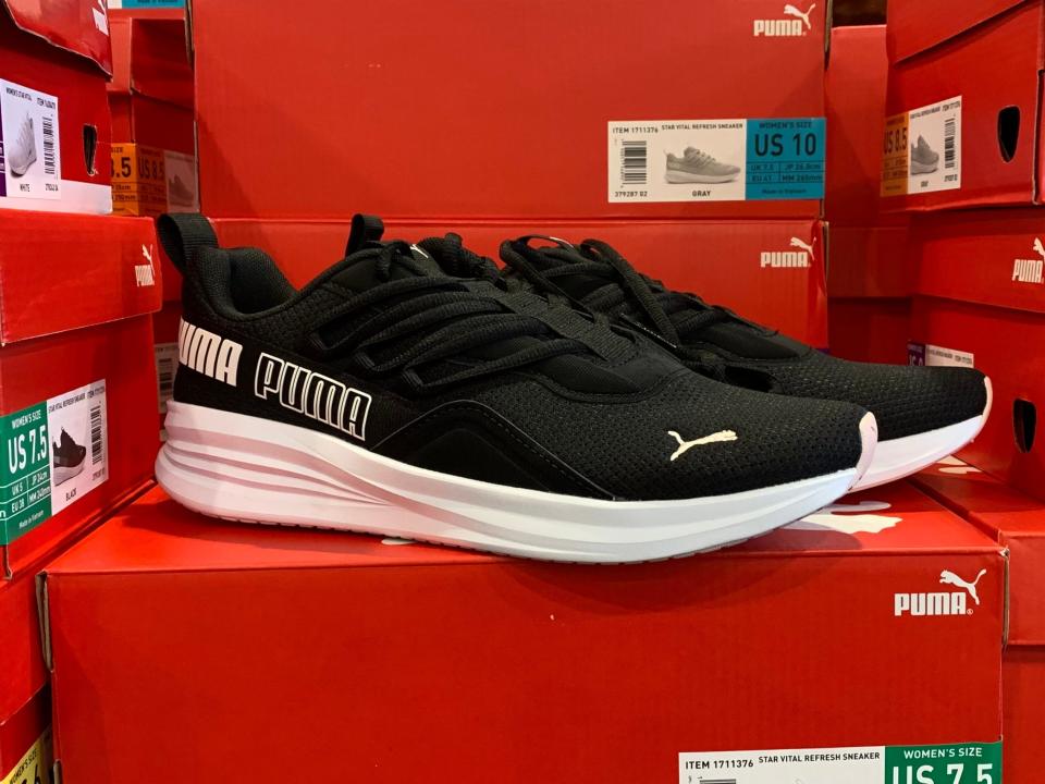 A pair of black and white Puma sneakers on a red box.