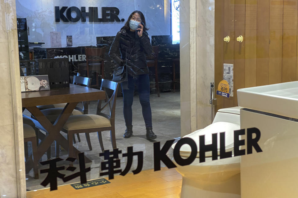 A woman wearing a face mask to help curb the spread of the coronavirus talks on her phone inside a Kohler shop in Beijing, Tuesday, March 16, 2021. Chinese state TV has criticized bathroom fixtures brand Kohler and automaker BMW for using facial recognition to identify customers in a possible violation of privacy rules that took effect this year. (AP Photo/Andy Wong)