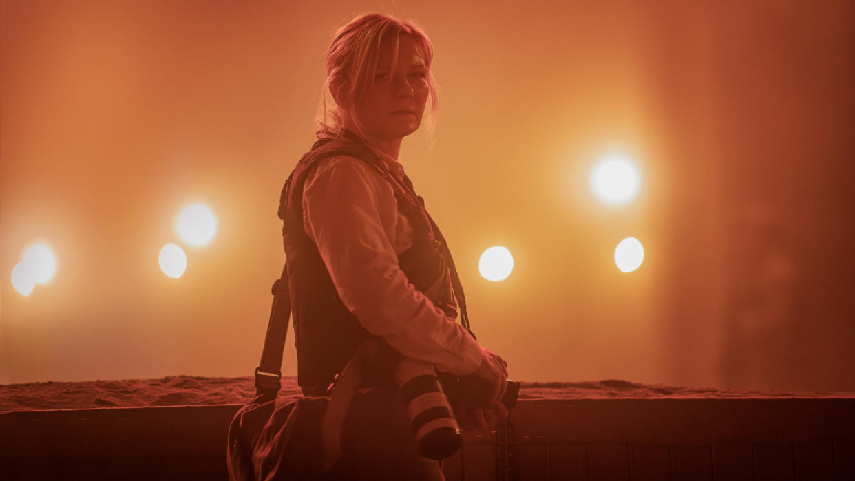  Kirsten Dunst looks back at the camera in a hazy orange environment in Civil War. 