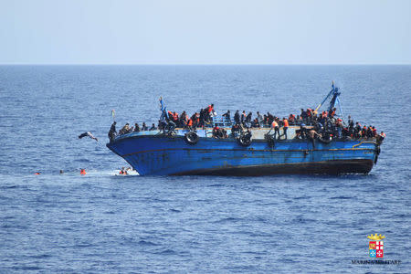 Migrants are seen on a capsizing boat before a rescue operation by Italian navy ships "Bettica" and "Bergamini" (unseen) off the coast of Libya in this handout picture released by the Italian Marina Militare on May 25, 2016. Marina Militare/Handout via REUTERS
