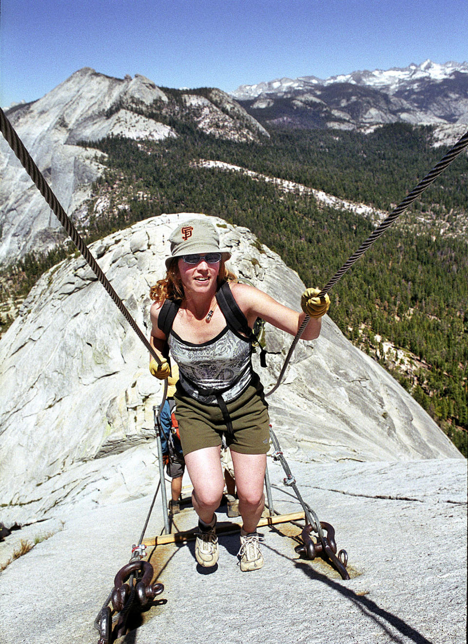 FILE - In this June 6, 2004 file photo, Thea Roberts of Oakland, Calif., pulls herself up the cable route on the way to the summit of Half Dome, in Yosemite National Park. The trail of dirt and hundreds of feet of twisted metal cables might not immediately conjure an image of something worthy of historical preservation. But when the trail leads to the iconic Half Dome in Yosemite National Park and the cables allow armchair wilderness lovers to ascend the once-inaccessible granite monolith, the significance becomes enough for listing on the National Register of Historic Places. While such a move might go unnoticed, as it did last month, the timing and significance are critical as Half Dome hikers and wilderness advocates await the park’s final assessment of a plan to permanently limit access to a place on many outdoor lovers’ bucket lists. (AP Photo/Robert F. Bukaty)