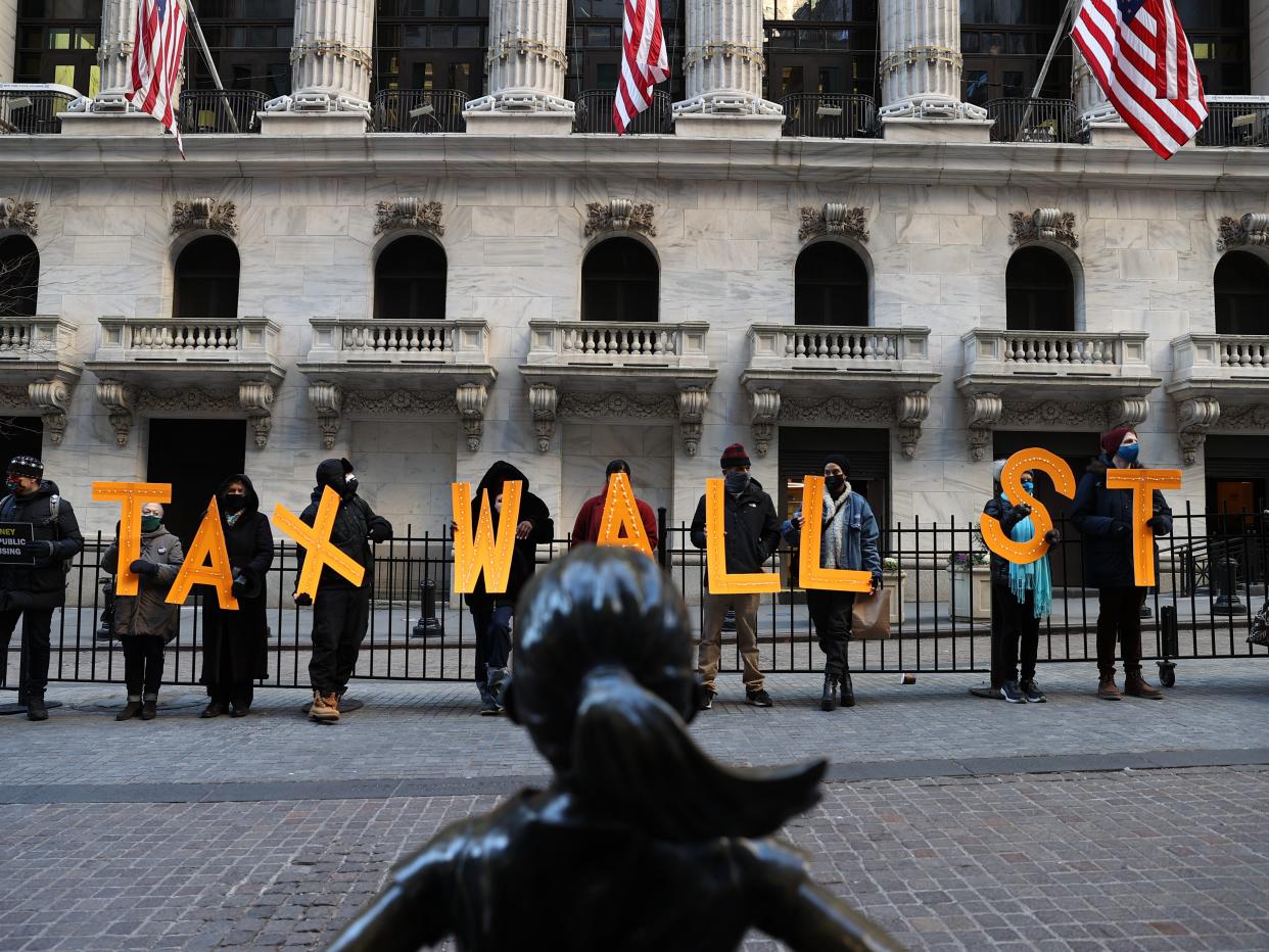 A group of demonstrators are gathered by the New York Stock Exchange