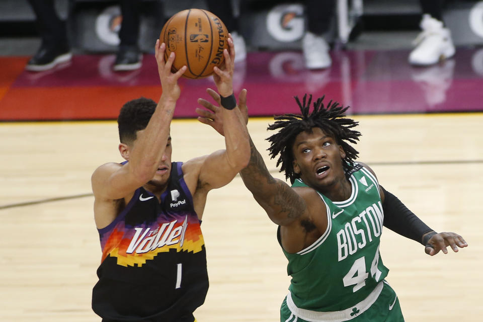 Boston Celtics forward Robert Williams III (44) reaches to knock the ball away from Phoenix Suns guard Devin Booker (1) during the second half of an NBA basketball game, Sunday, Feb. 7, 2021, in Phoenix. (AP Photo/Ralph Freso)