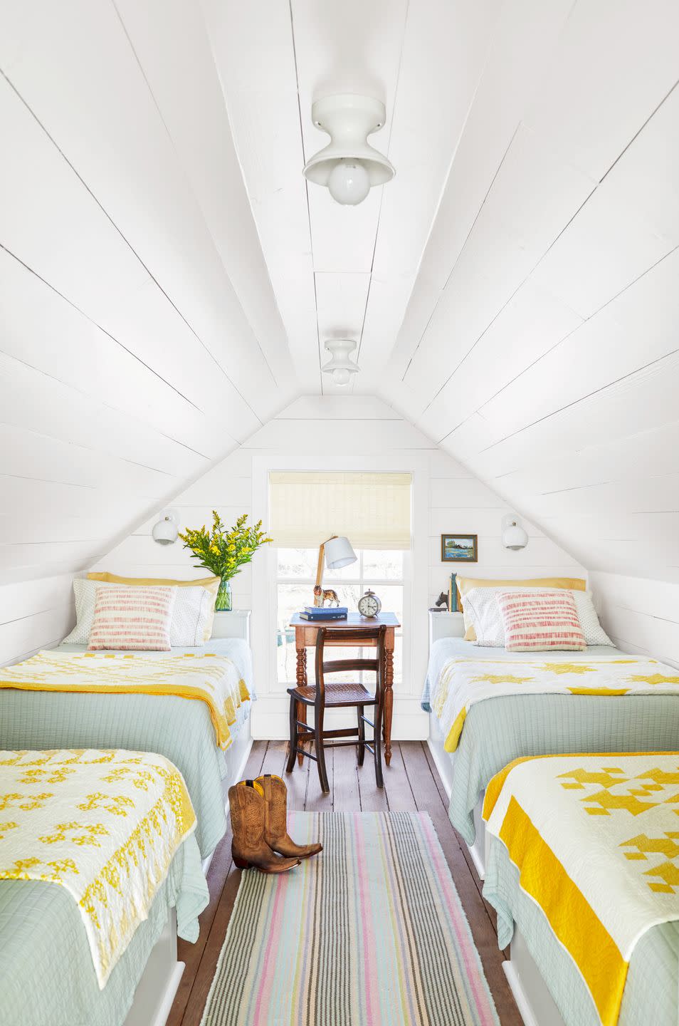 white attic bedroom with yellow pieced quilts on the four beds