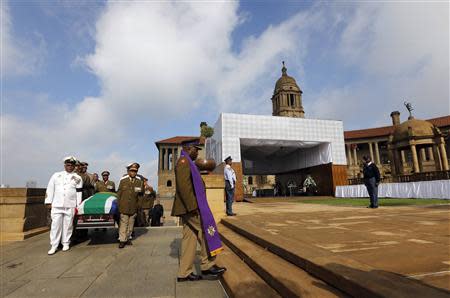 Military personnel carry the remains of the late Nelson Mandela upon arrival at the Union Buildings in Pretoria, December 11, 2013, as members of the Mandela family follow behind. REUTERS/Kim Ludbrook/Pool