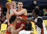 Denver Nuggets center Nikola Jokic, left, looks to pass the ball as Miami Heat center Bam Adebayo defends in the first half of an NBA basketball game Wednesday, April 14, 2021, in Denver. (AP Photo/David Zalubowski)