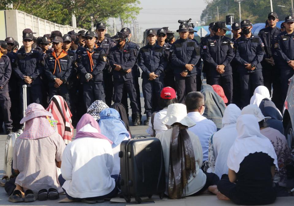 Buddhist pray in front of policemen outside the Wat Dhammakaya temple in Pathum Thani province, Thailand, Thursday, Feb. 16, 2017. Hundreds of police are carrying out a raid on the headquarters temple of a controversial Buddhist temple sect to detain its chief, a monk facing criminal charges including accepting $40 million in embezzled money. (AP Photo/Sakchai Lalit)