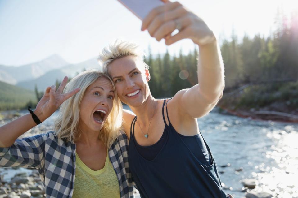 A couple poses for a selfie together against a river